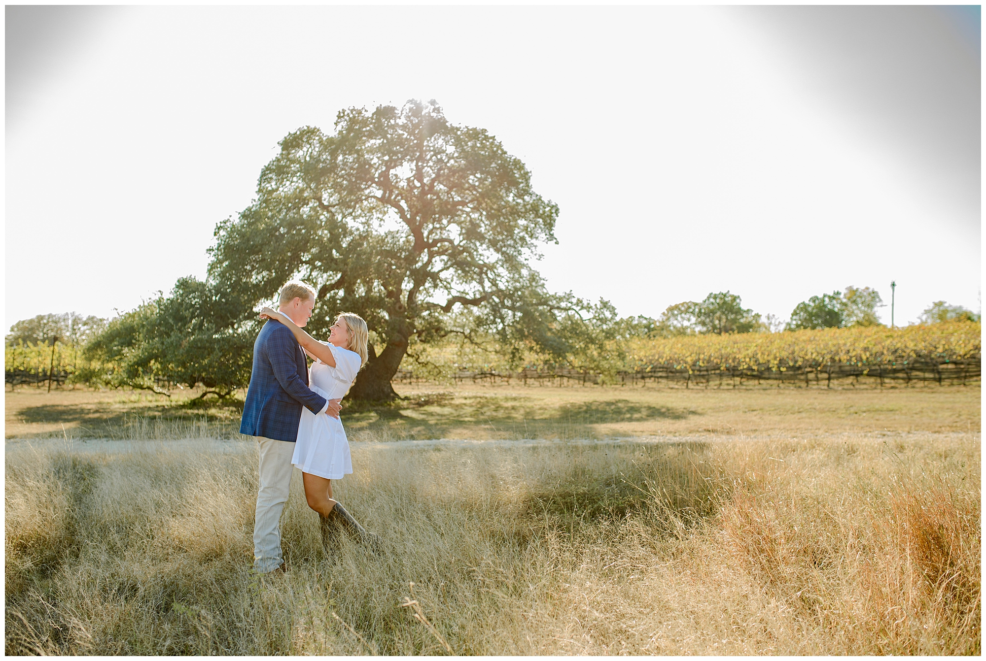 Engaged couple laughing together during their Hill Country engagement session surrounded by soft autumn light.