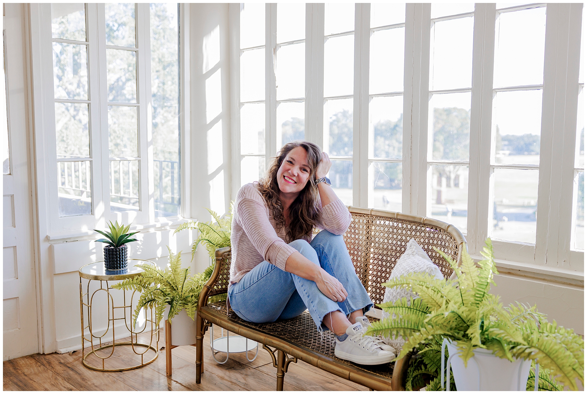 Portrait of Megan Smart sitting in natural window light surrounded by greenery, celebrating her 40th birthday.